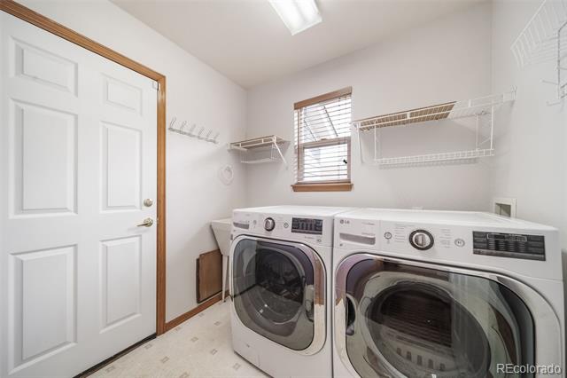 Laundry room with front-loading washer and dryer beneath white wire storage shelves.