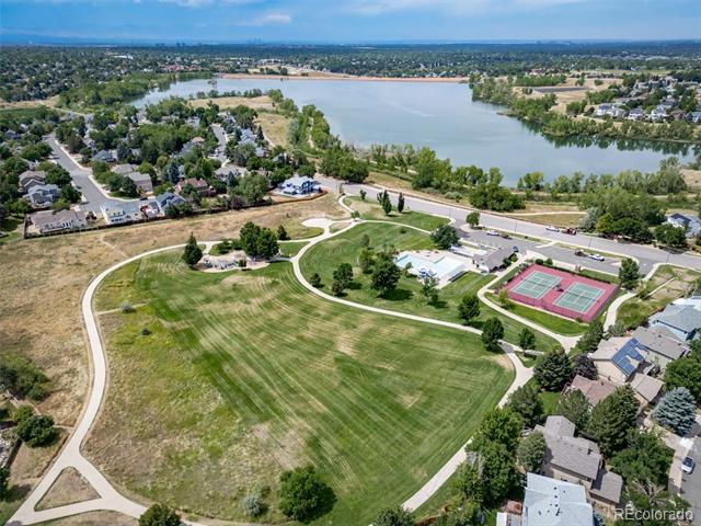 Neighborhood park with tennis courts and walking paths beside a lake.