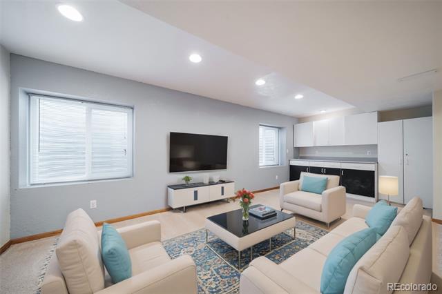 Living room with white sofas, turquoise cushions, blue patterned rug, wall-mounted television, and fireplace.