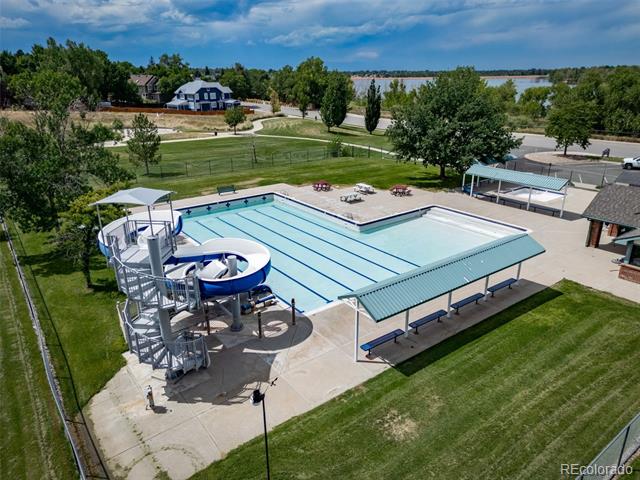 Neighborhood pool with lap lanes, a twisting waterslide, and covered seating beside a lake.