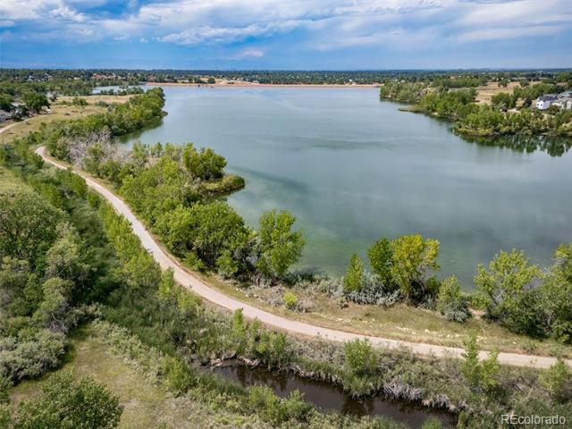 Aerial view of a lake bordered by trees and a winding shoreline path.