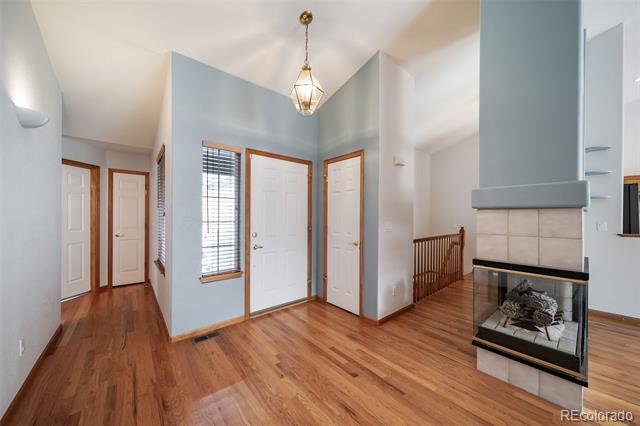 Entryway with hardwood floors, a tiled fireplace, and a white front door.