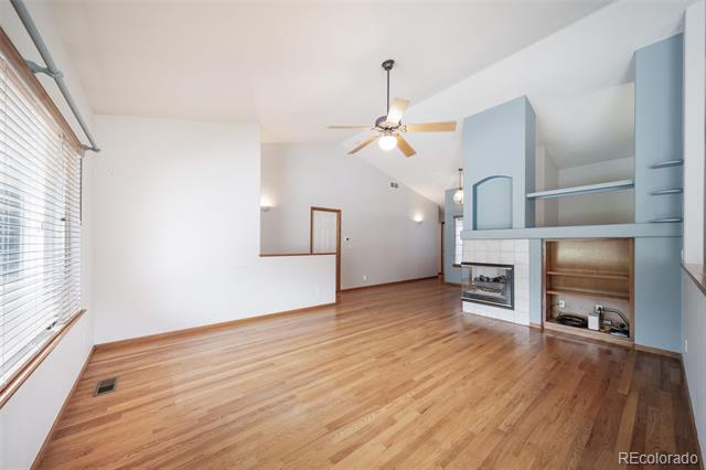 Living room with hardwood floors, vaulted ceiling, and fireplace with built-in shelving.
