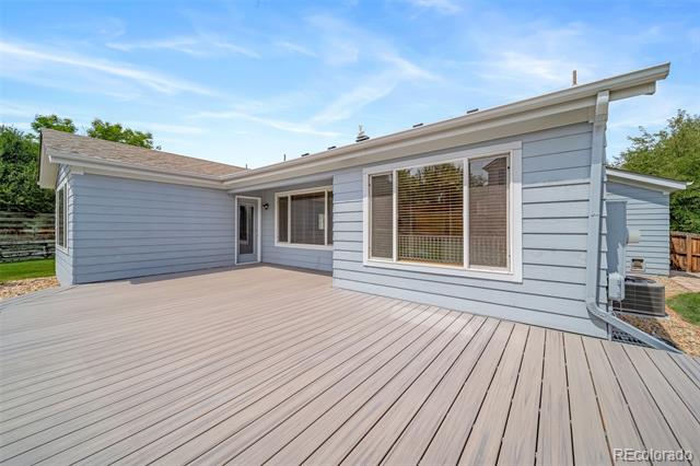Rear of a light blue home with a wide, empty deck and large white-trimmed windows.