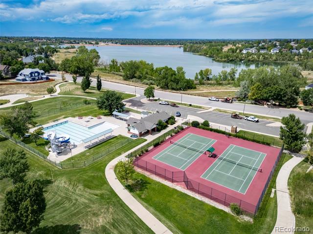 Aerial view of community swimming pool and tennis courts beside a lake.