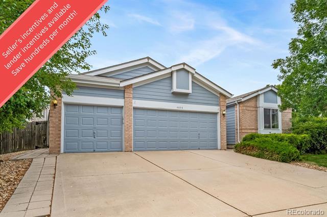 Home exterior with two garage doors, blue-gray siding, brick accents, and a wide concrete driveway.