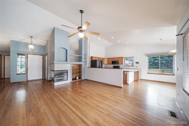 Open-plan living room and kitchen with hardwood floors, a fireplace, and a kitchen island.