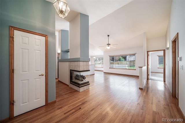 Open living area with hardwood floors, a corner fireplace, and large windows.