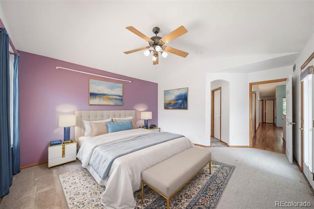 Bedroom with a purple accent wall, large bed, and wood-blade ceiling fan.