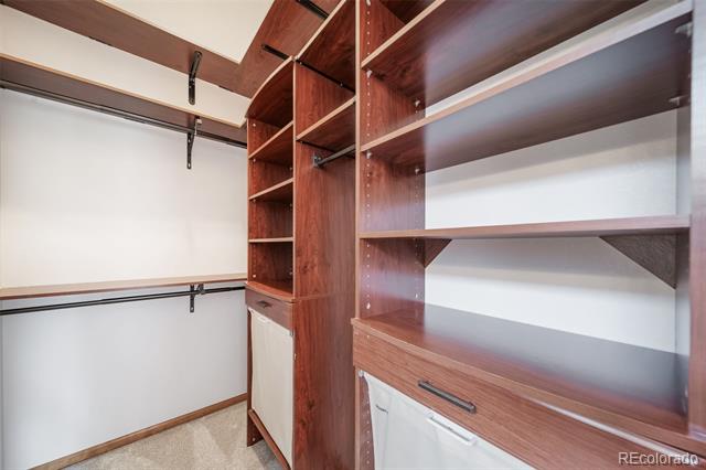 Walk-in closet with built-in wood shelving, drawers, and hanging rods.