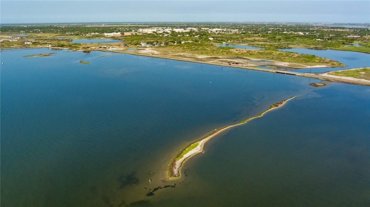 Aerial view of a coastal bay with a narrow sandy spit and distant shoreline.