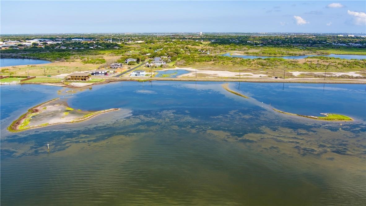 Aerial view of a coastal lagoon, with shoreline homes and wetlands in the distance.