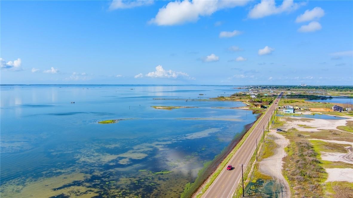 Aerial view of a coastal lagoon and shoreline road beside scattered homes.