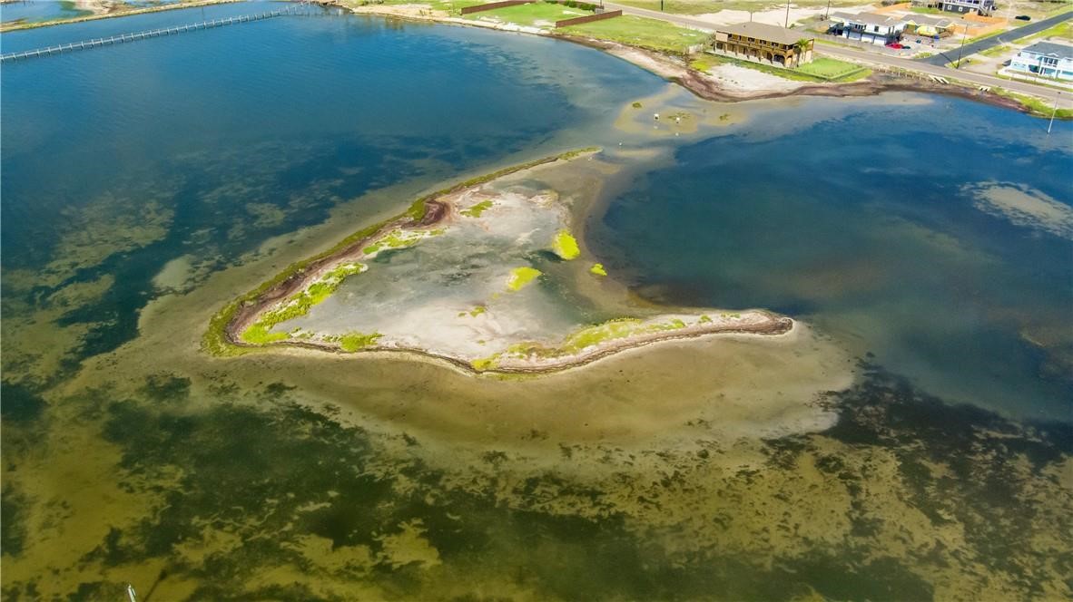 Aerial view of a sandy shoreline peninsula surrounded by shallow coastal water.