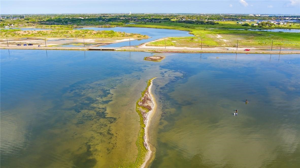 Aerial view of a narrow grassy sand spit extending into a shallow coastal bay.
