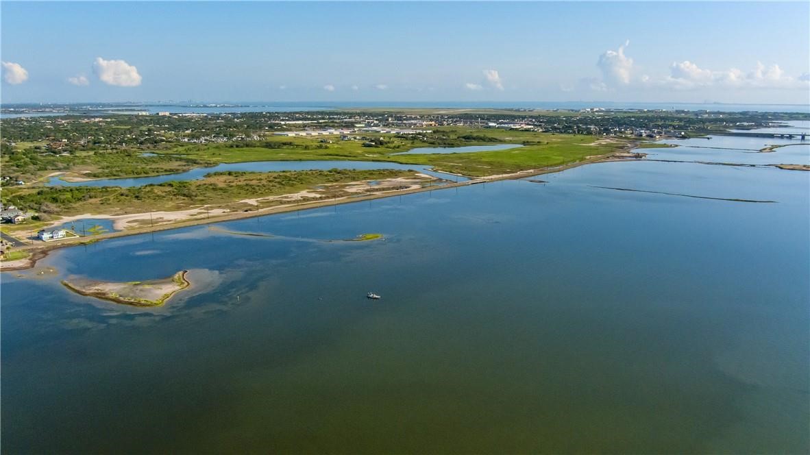 Aerial view of coastal water and marshland, with small islands and development along the distant shore.