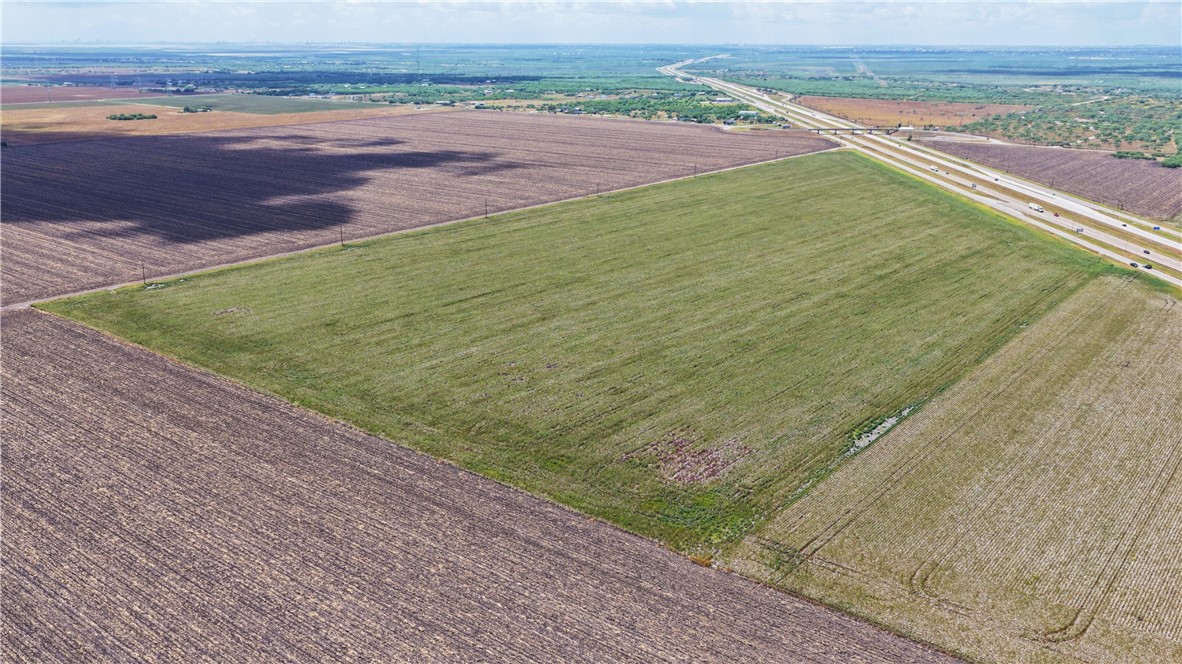 Aerial view of a green field beside a highway, surrounded by cultivated farmland.
