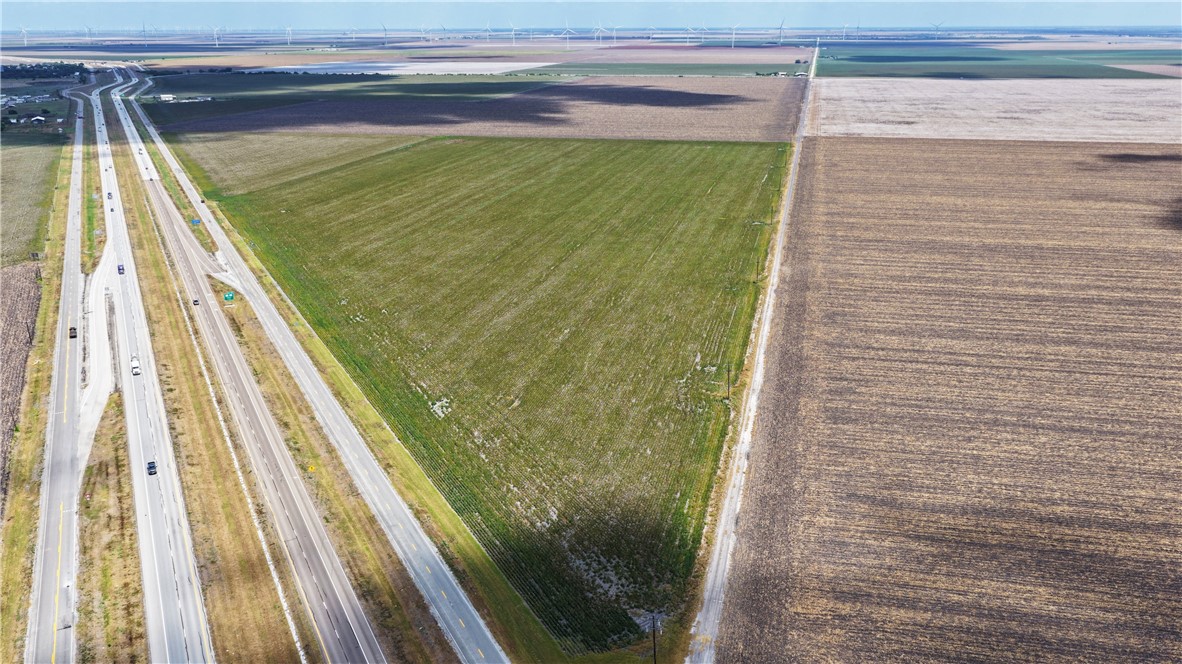Aerial view of undeveloped land beside a divided highway, surrounded by agricultural fields.
