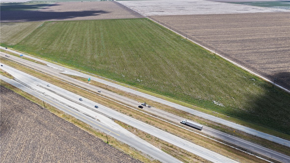 Aerial view of agricultural fields beside a divided highway with passing traffic.