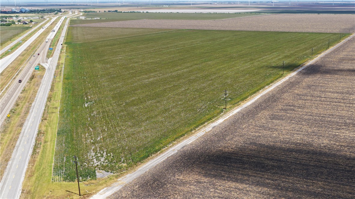 Aerial view of cultivated land beside a divided highway and neighboring plowed fields.