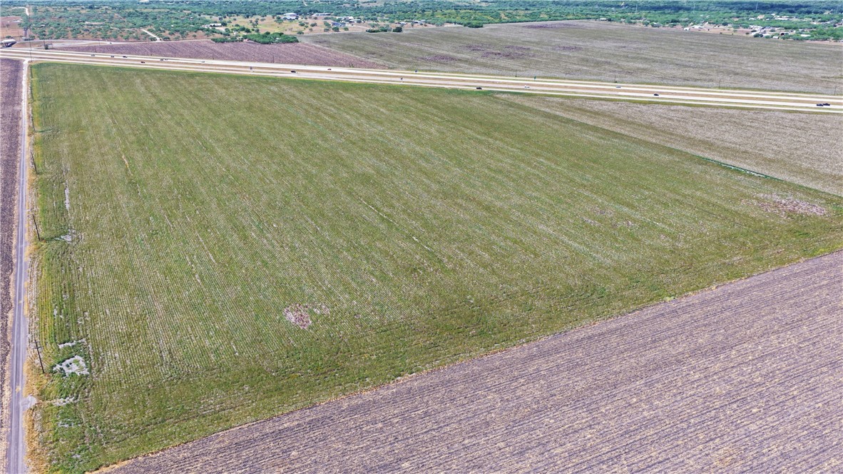 Aerial view of a green field bordered by a divided highway and rural road.