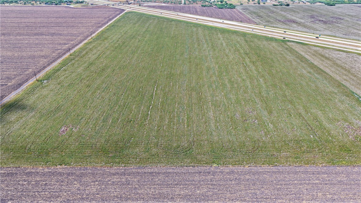 Aerial view of a green agricultural tract bordered by plowed fields and a divided highway.