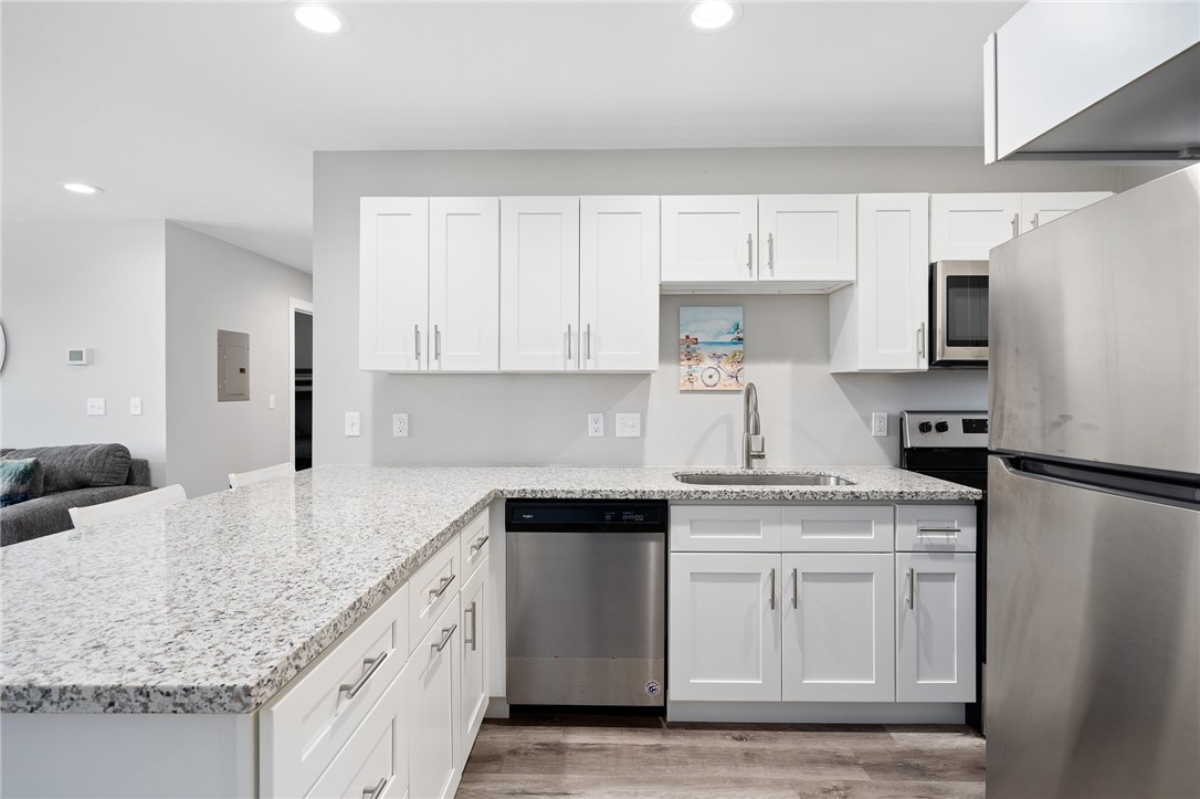 Modern kitchen with white cabinets, granite counters, stainless steel appliances, and a wide peninsula.