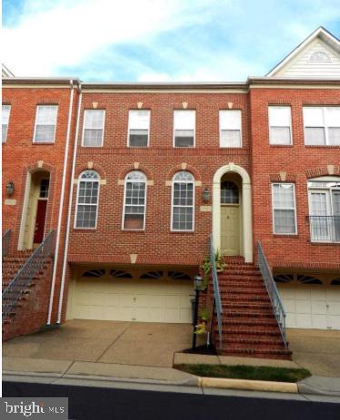 Red-brick townhome with front stairs and two garage doors beneath the entrance.