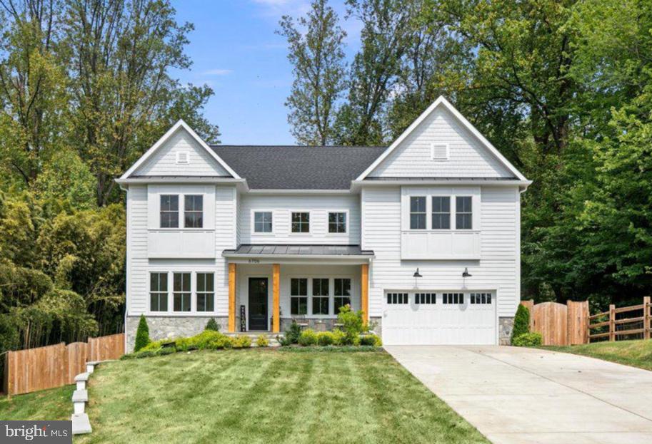 White two-story house with twin front gables, a stone foundation, attached garage, and broad front lawn.