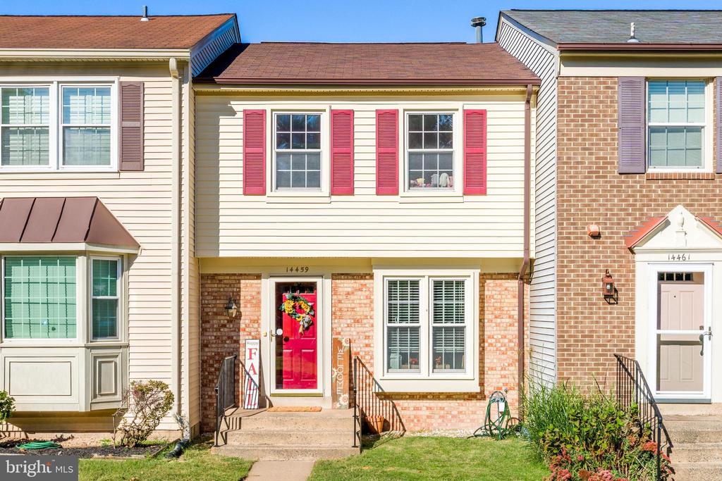 Townhouse with cream siding, red shutters, and a bright red front door with a wreath.