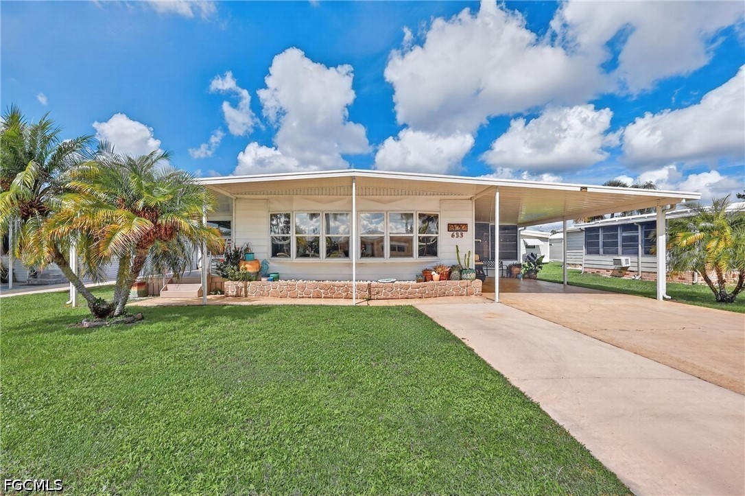Single-story home with a covered carport, palm trees, and a stone-edged planter.