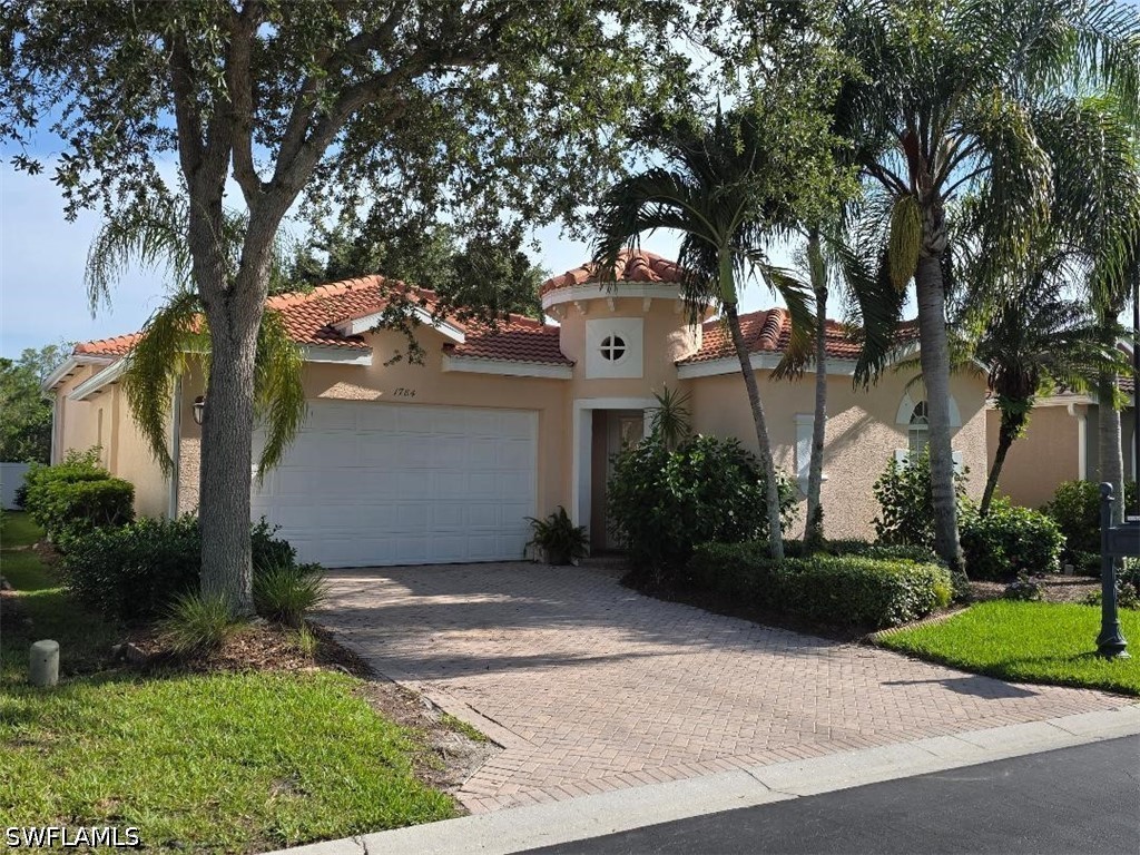 Stucco home with a red tile roof, palm trees, and a brick-paver driveway.