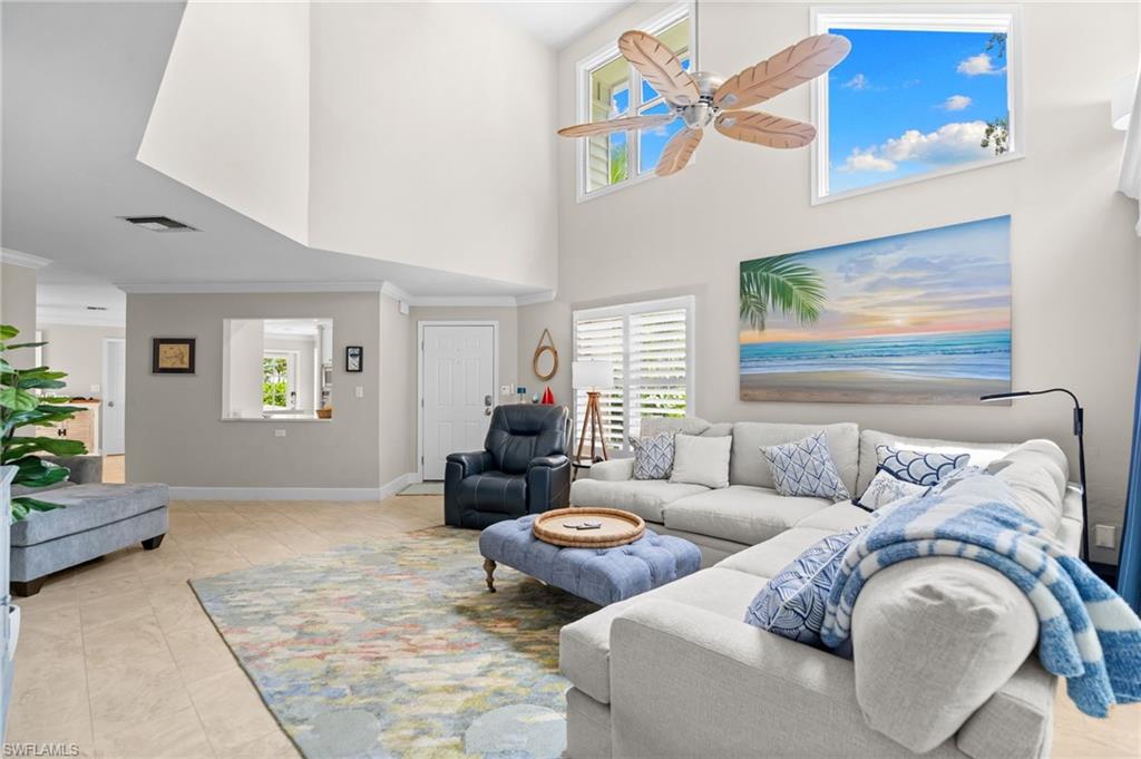 Vaulted living room with a white sectional sofa, blue ottoman, and high windows.