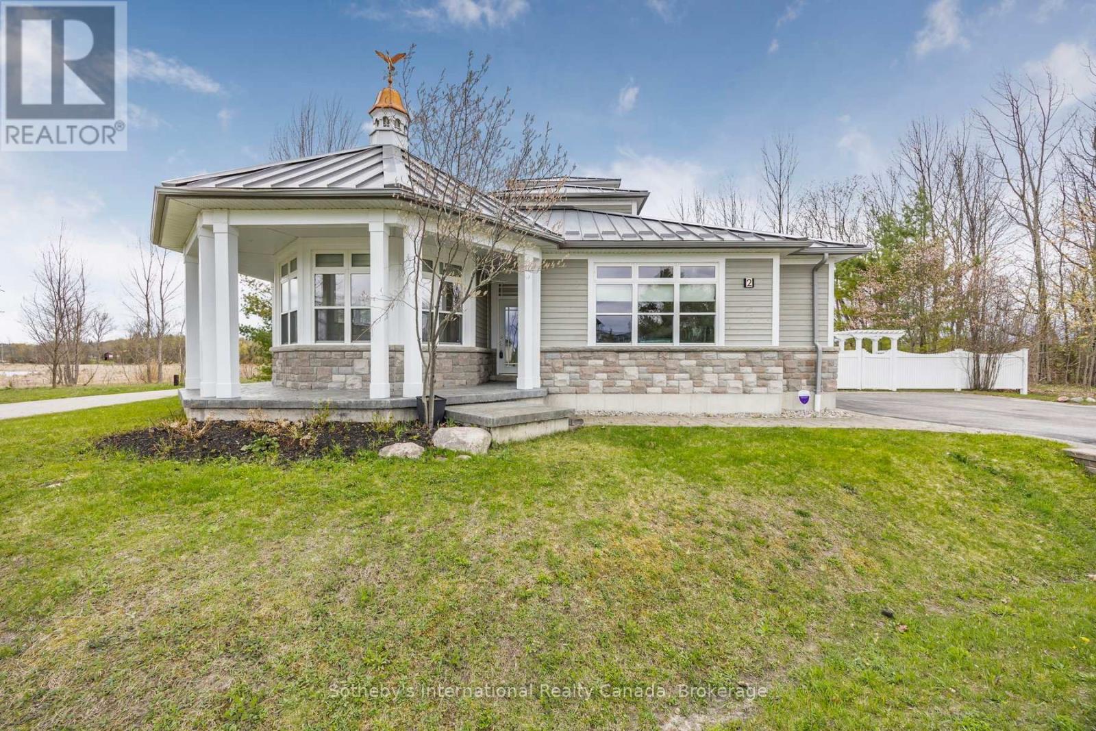 Single-story home with a stone facade, broad covered porch, and metal roof topped by a cupola.