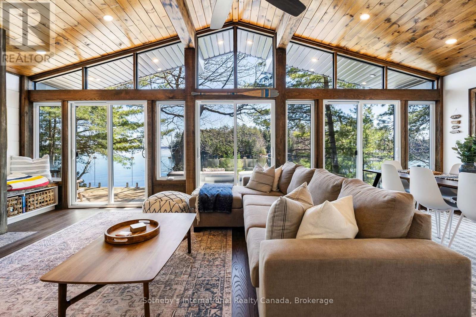 Furnished living room with vaulted wood ceiling, expansive windows, and a lake view.