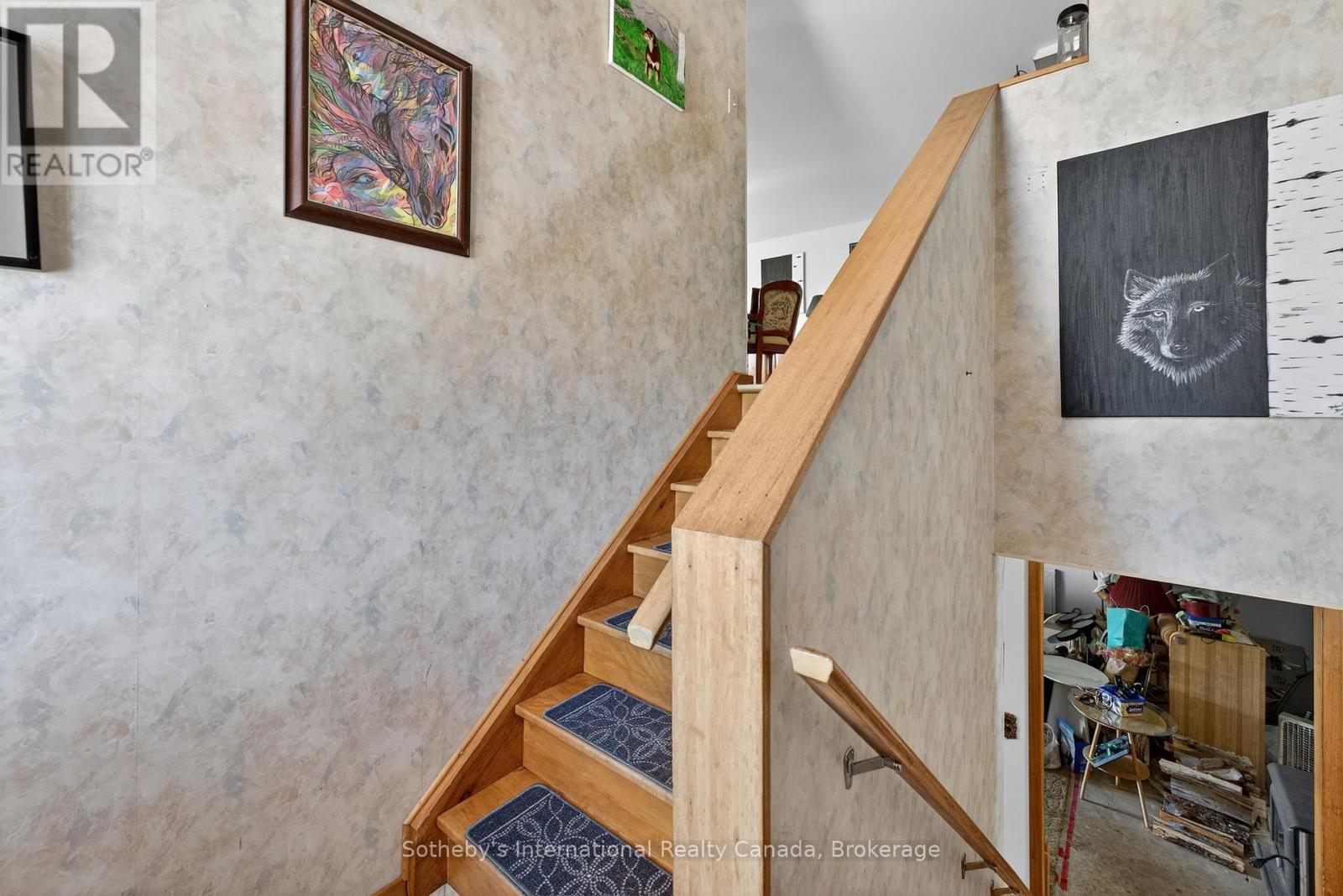 Wooden staircase with blue patterned stair runners and framed animal artwork.