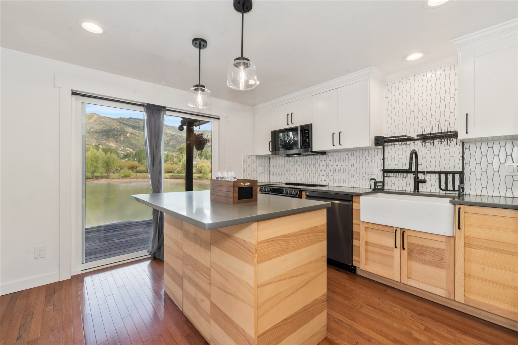 Modern kitchen with a wood island and views of water and mountains through sliding glass doors.