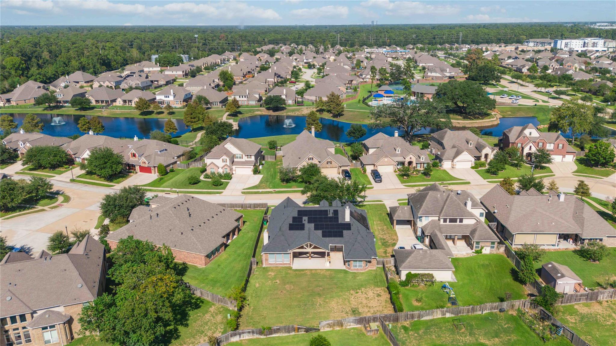 Aerial view of the neighborhood, with a pond, fountains, and community pool behind the homes.