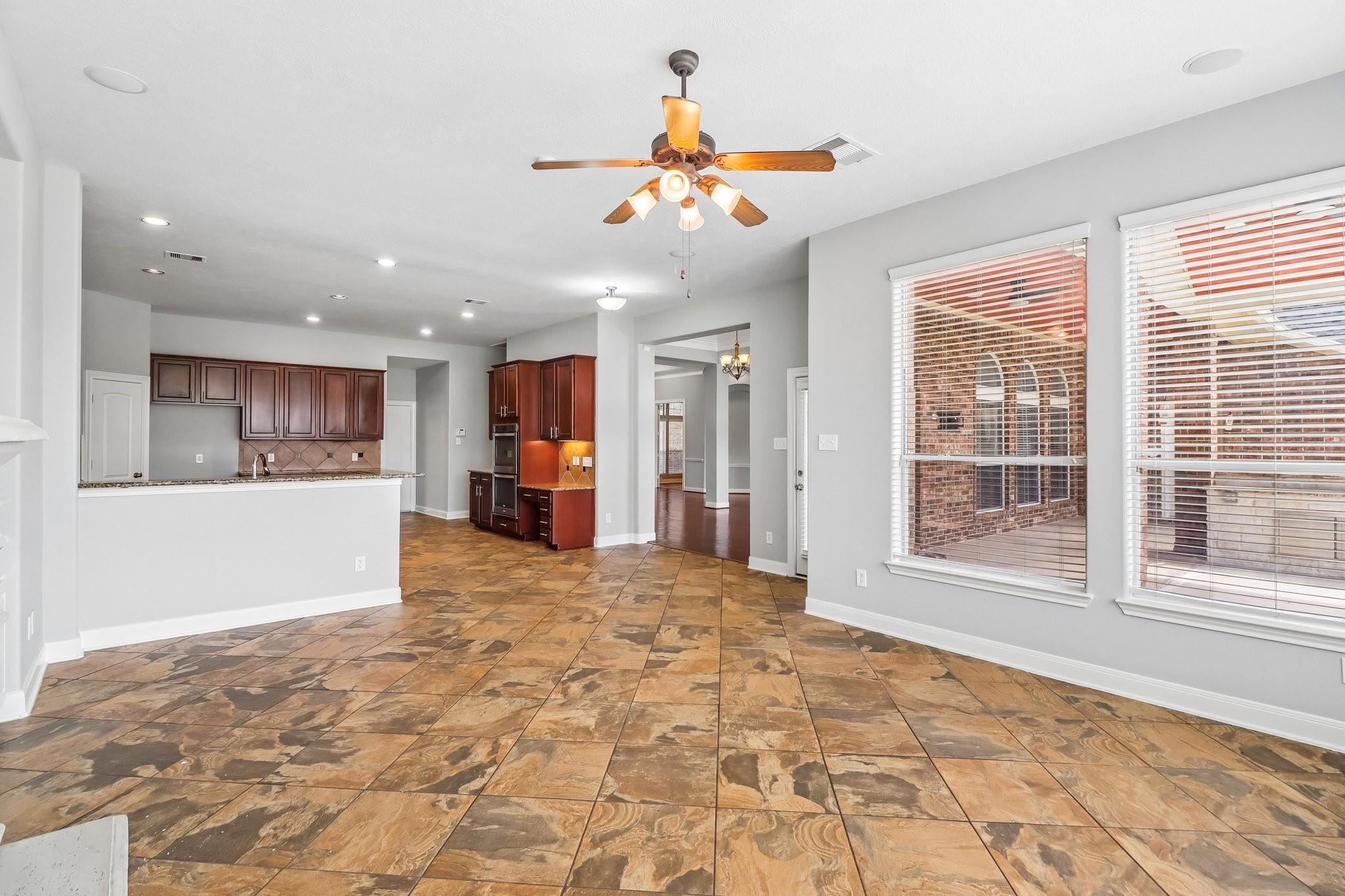 Open kitchen and dining area with dark wood cabinets, patterned tile floors, and large windows.