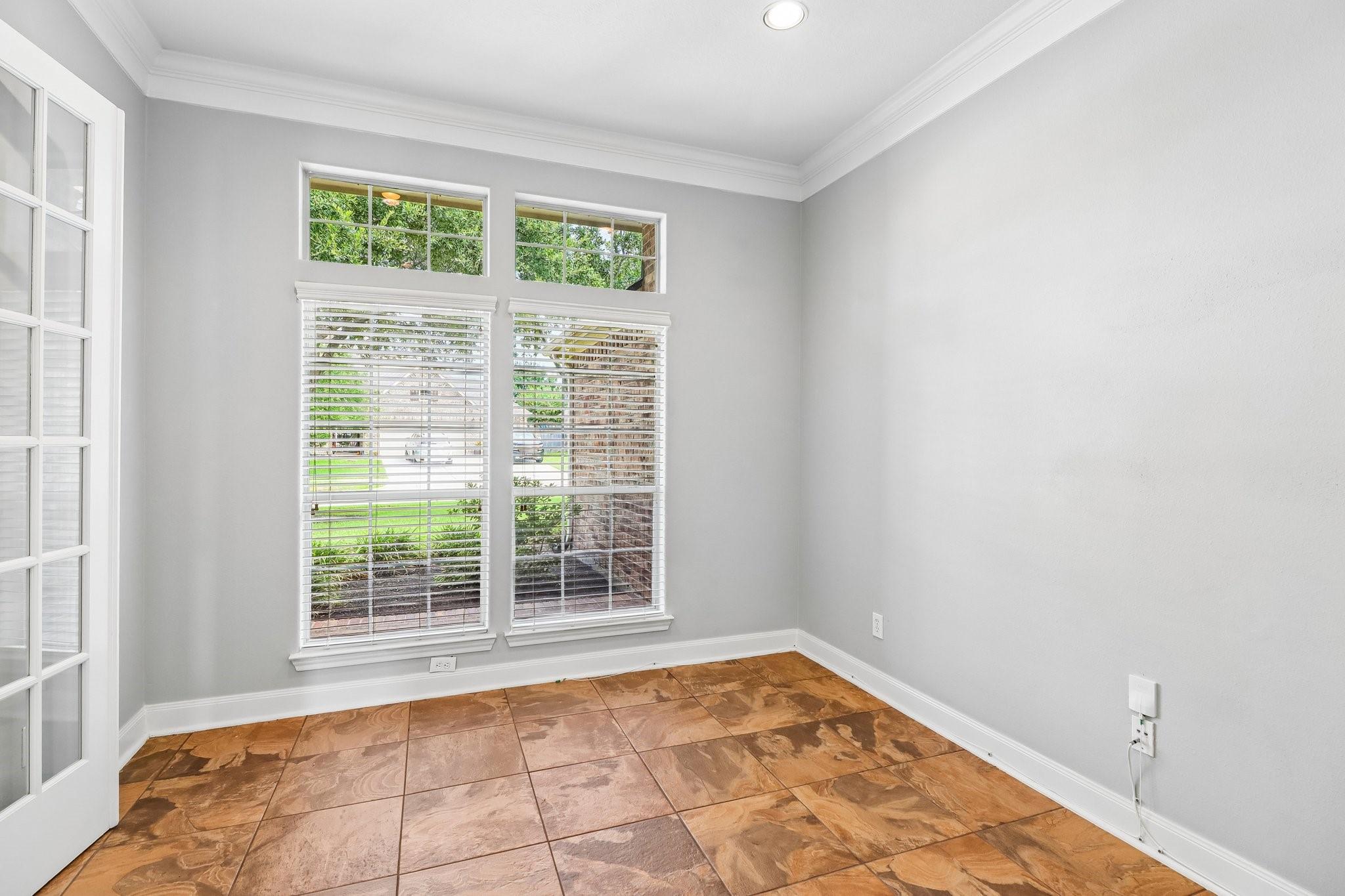 Empty room with patterned tile flooring and tall windows with blinds.