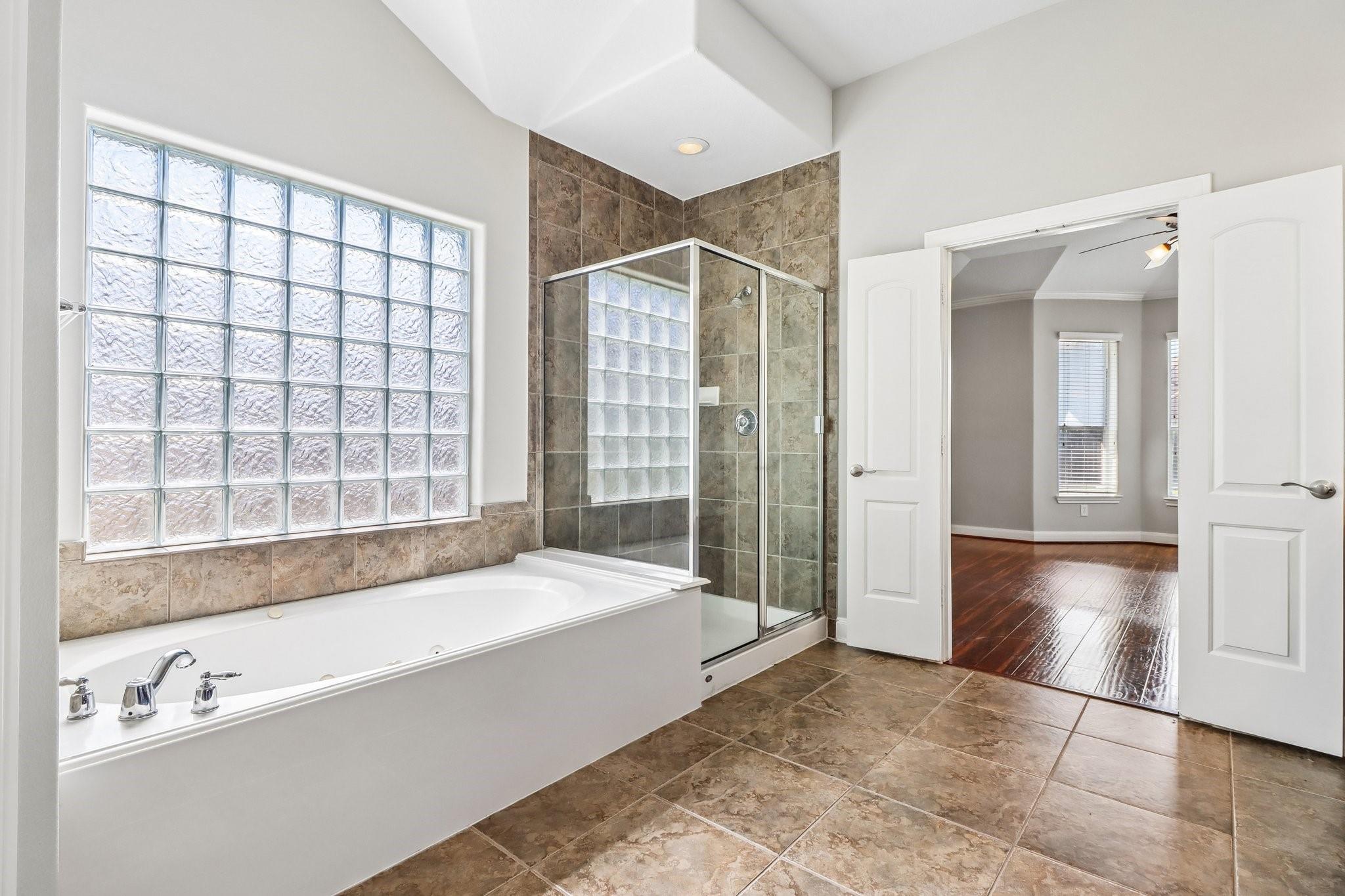 Bathroom with a soaking tub beneath a glass-block window and a glass-enclosed shower.