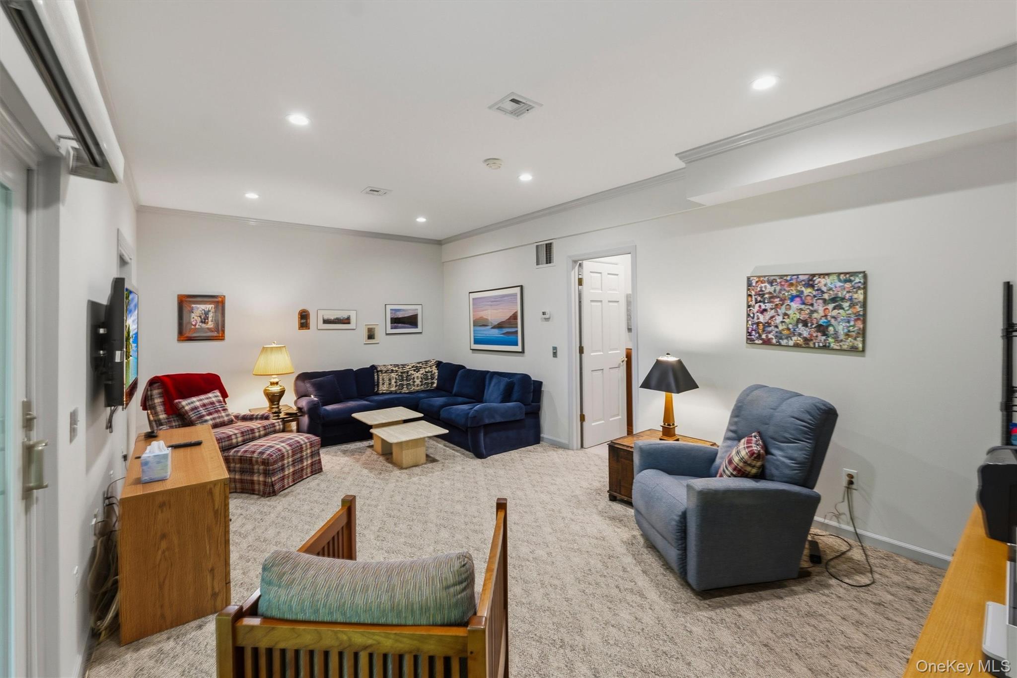 Furnished living room with a navy sectional, plaid chairs, and blue recliner.