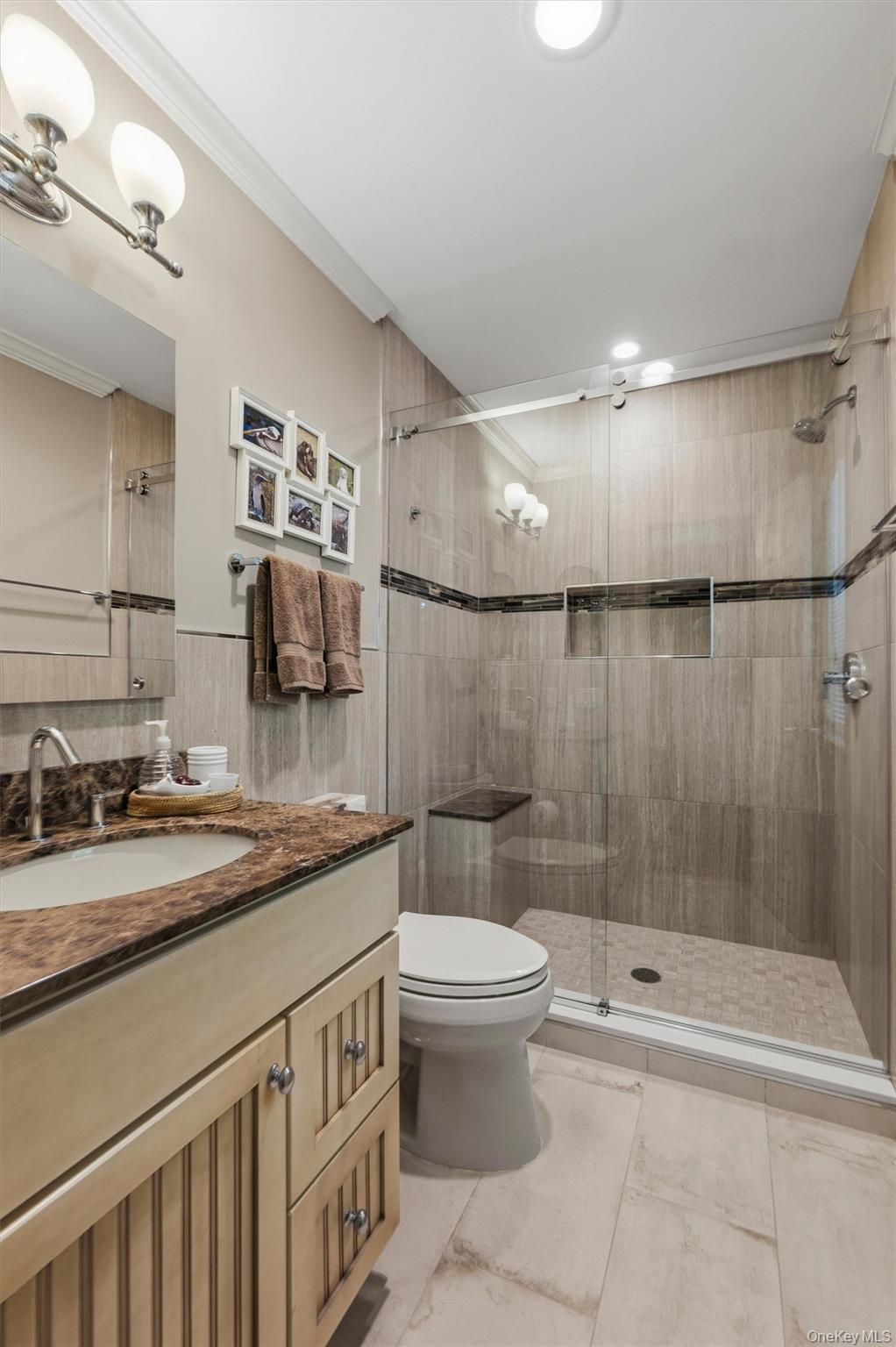 Bathroom with a glass-enclosed tiled shower, built-in niche, and marble-look vanity.