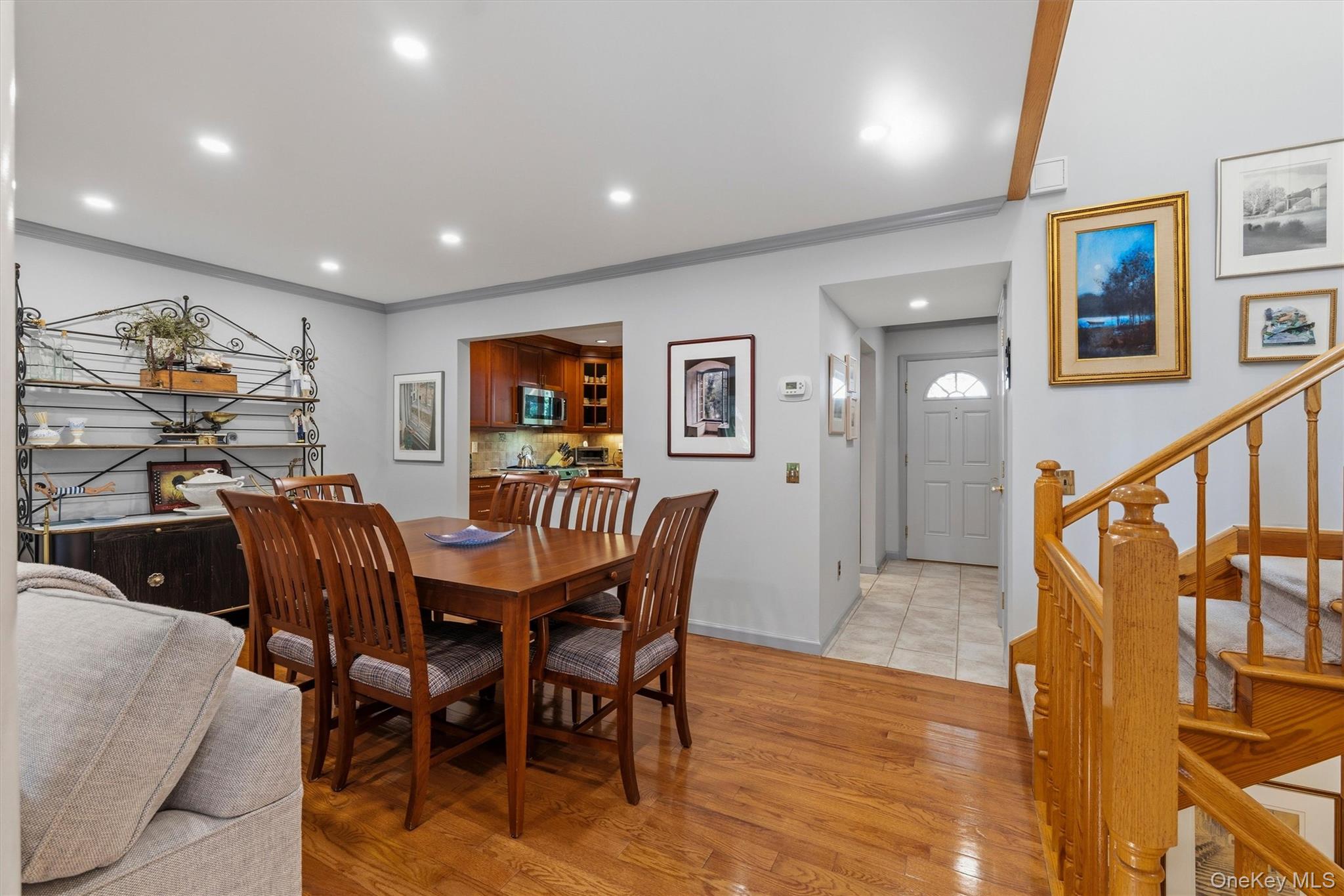 Dining area with a wooden table and chairs, hardwood floors, and a staircase with a wooden railing.