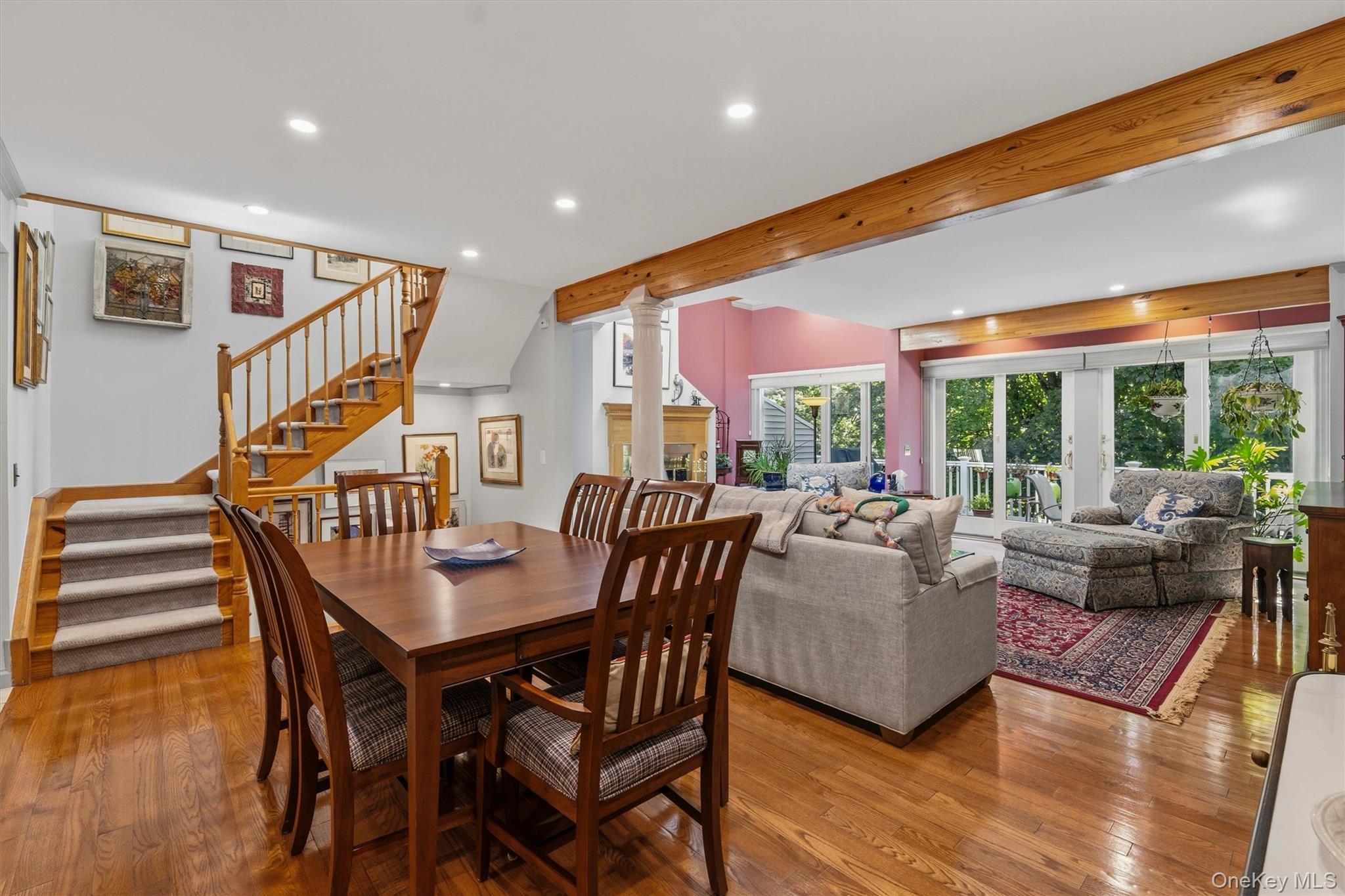 Open-plan living and dining room with hardwood floors, exposed beams, and sliding glass doors.