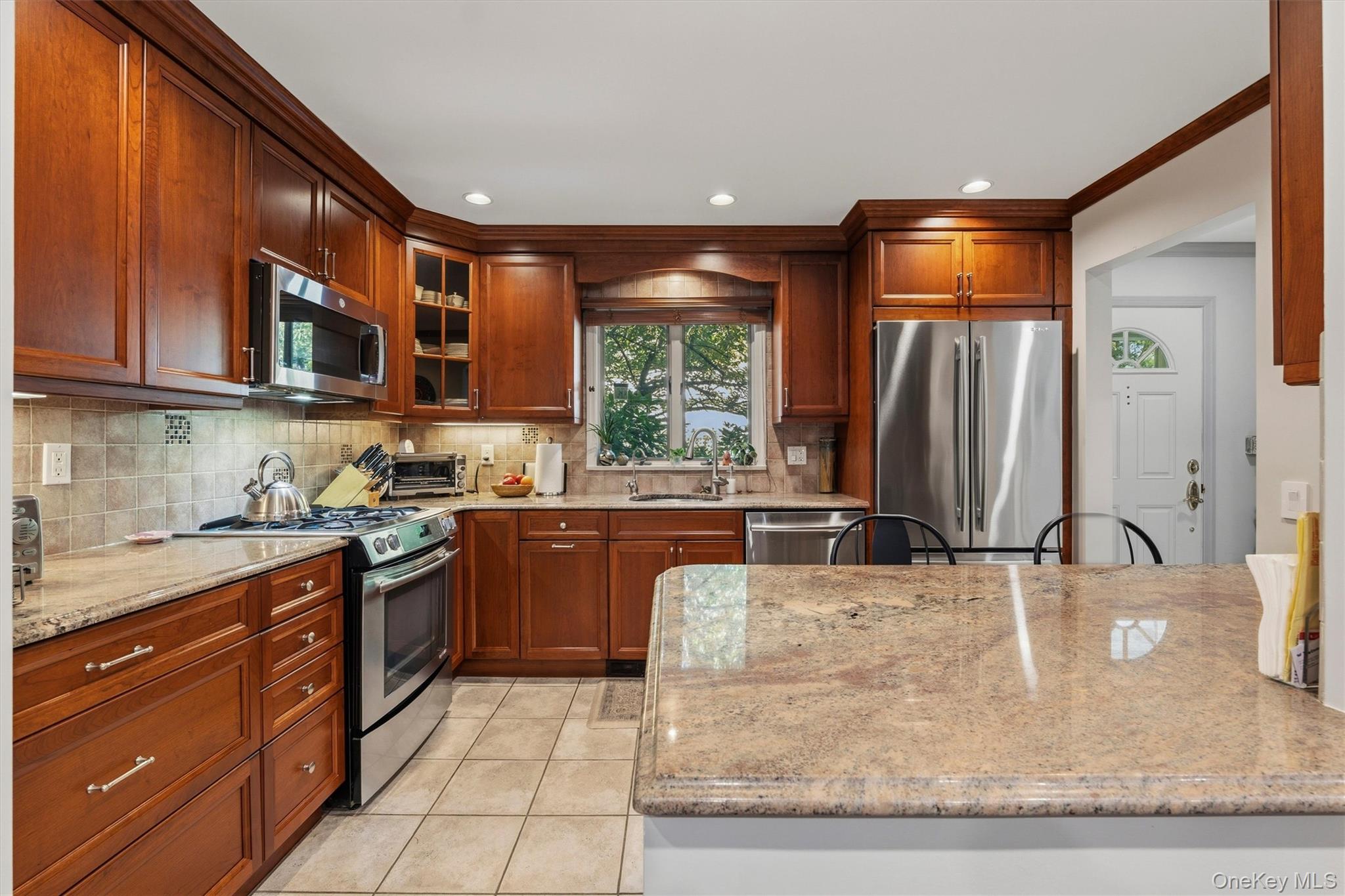Kitchen with cherry cabinets, granite island, and stainless steel appliances.