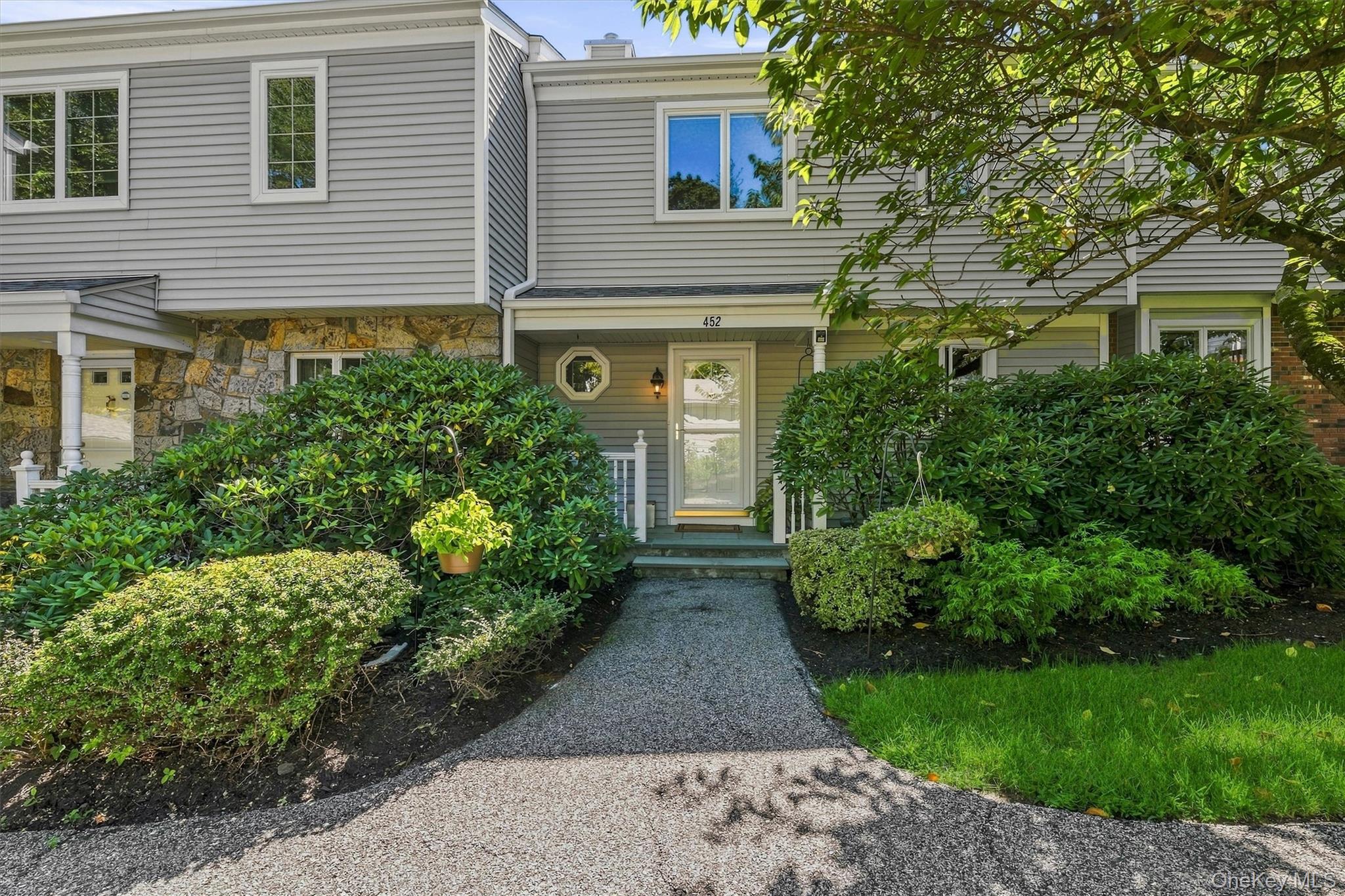 Gray-sided home with stone accents and a shrub-lined gravel path leading to the covered front porch.