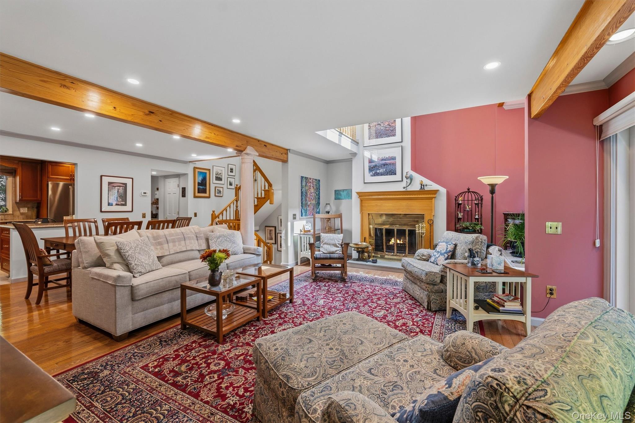 Living room with exposed wood beams, a fireplace, and a red accent wall.