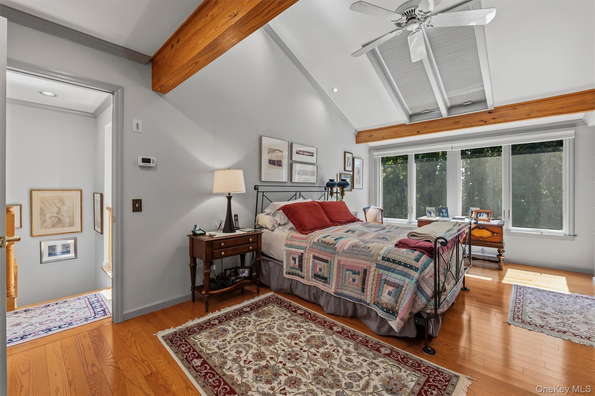 Bedroom with a patchwork quilt, vaulted ceiling, exposed beams, and skylights.