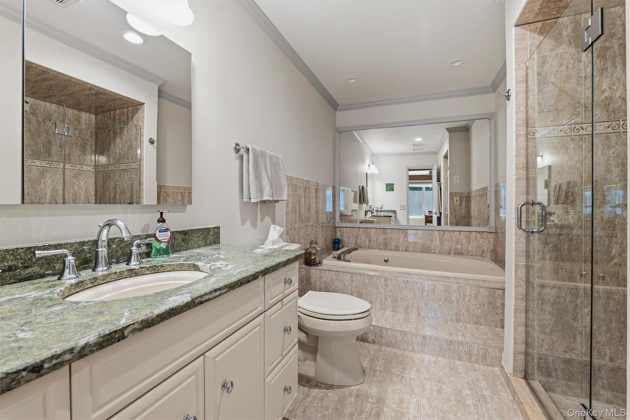 Bathroom with a green granite vanity, soaking tub, and glass-enclosed tiled shower.